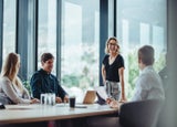 Office colleagues having casual discussion during meeting in conference room. Group of men and women sitting in conference room and smiling.