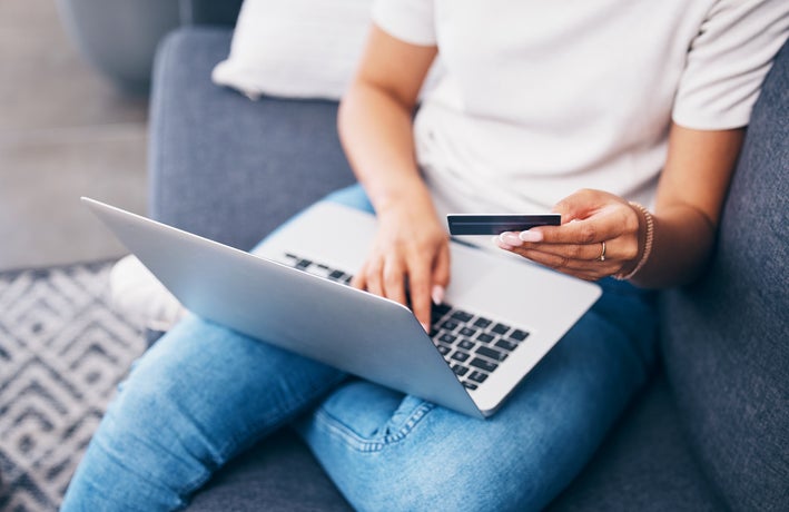 Online shopping, laptop or hands with credit card for financial digital payment while relaxing on sofa at home. Zoom, finance or girl typing ecommerce subscription discount code, sales offer or deal.