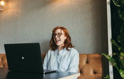 Woman speaks loudly on a Zoom call while sat in a coffee shop