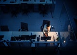Introverted leader sat behind the desk alone at night