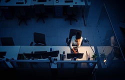 Introverted leader sat behind the desk alone at night