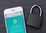 WhatsApp open on a smartphone next to a padlock