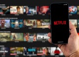 Male hand holding a smartphone with Netflix App on the screen with de website blurred on background. Rio de Janeiro, RJ, Brazil. August 2021.