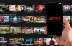 Male hand holding a smartphone with Netflix App on the screen with de website blurred on background. Rio de Janeiro, RJ, Brazil. August 2021.
