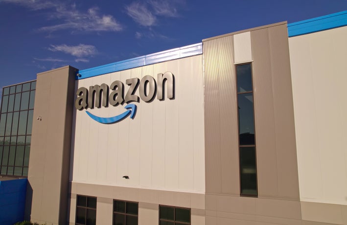 Toronto, Ontario, Canada - September 11, 2022: Amazon warehouse building headquarter and close-up logo of the company at golden hour evening. Technology company developed international e-commerce.