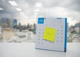 Calendar on an office desk, blocked out with a post-it note reading 