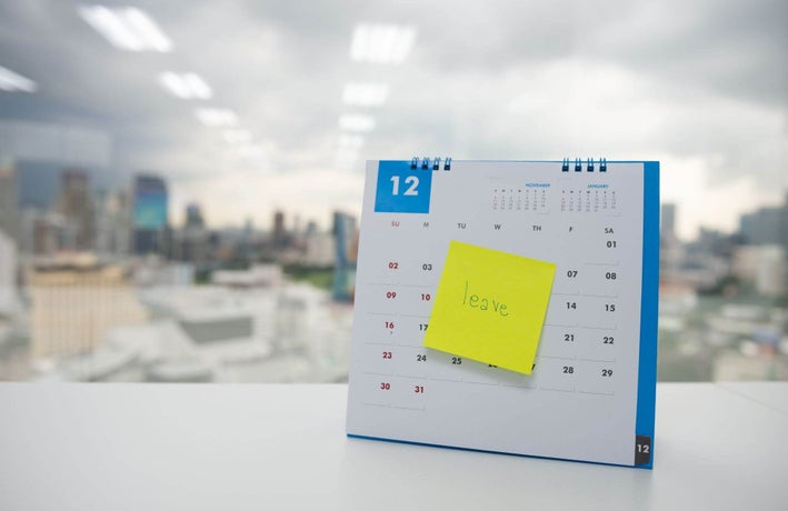 Calendar on an office desk, blocked out with a post-it note reading 