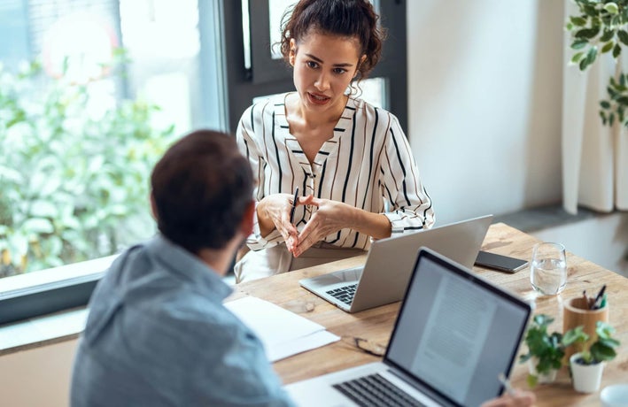 Consultant and client talking on table by large window