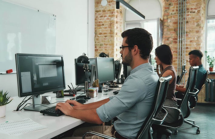 A row of employees sitting at desks using desktop computers