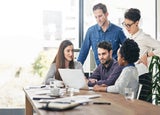 Group of employees standing around a single laptop