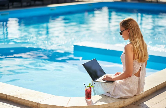 Woman sitting at a pool working on her laptop