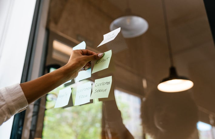 A single hand sticking written post it notes onto a window.