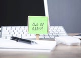 Note reading 'Out of office' on a work desk