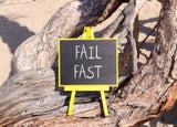 A blackboard sign sitting on a tree that reads 