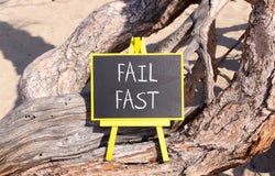 A blackboard sign sitting on a tree that reads 