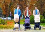 New dads pushing babies in prams through a park
