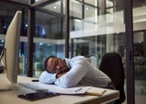 Man sleeping at office desk during work day