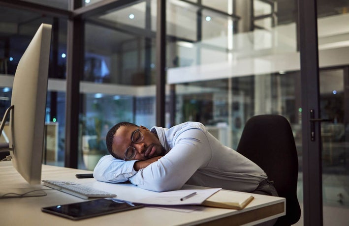 Man sleeping at office desk during work day