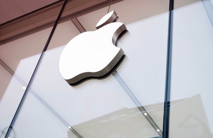 A close up shot of the outside of an Apple office with its logo displayed on front.