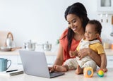Woman working on her laptop while holding a baby