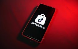 A smartphone device with a red backdrop displaying the TikTok Shop logo.