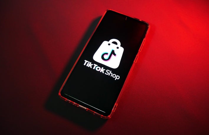 A smartphone device with a red backdrop displaying the TikTok Shop logo.