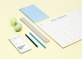 Yellow background with calendar, stationary supplies, and a phone showing online sales information