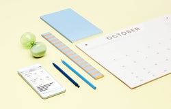 Yellow background with calendar, stationary supplies, and a phone showing online sales information