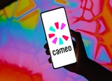 A hand holding up a smartphone device with the Cameo logo displayed on the screen.
