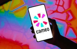 A hand holding up a smartphone device with the Cameo logo displayed on the screen.