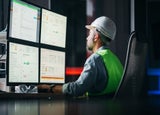 Construction worker looks at a computer screen showing various charts and graphs